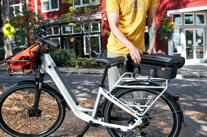 Man placing an electric bike battery in a case on a white electric bike.