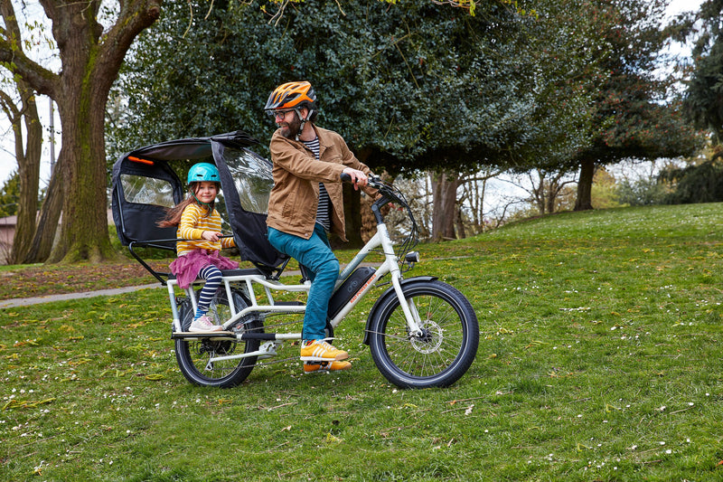 Man and child riding an ebike with rain cover